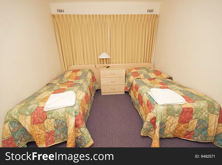 A hotel bedroom with two single beds, complete with quilts and blankets.