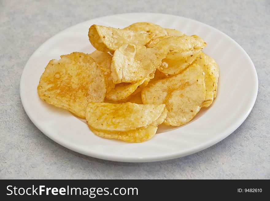 Barbeque flavored potato chips laid out nicely on a porcelain plate.