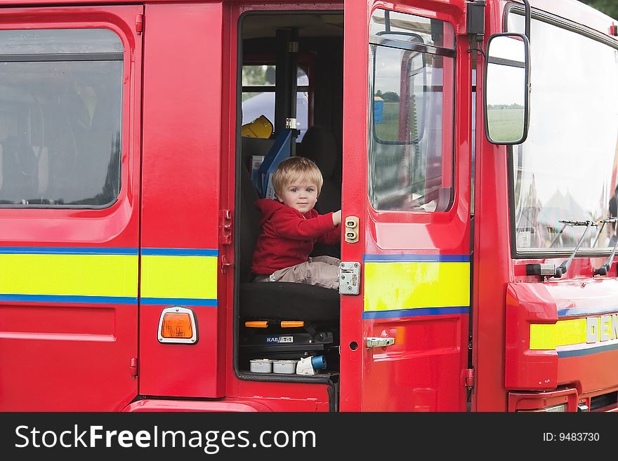 Child pretending to drive a red fire engine. Child pretending to drive a red fire engine