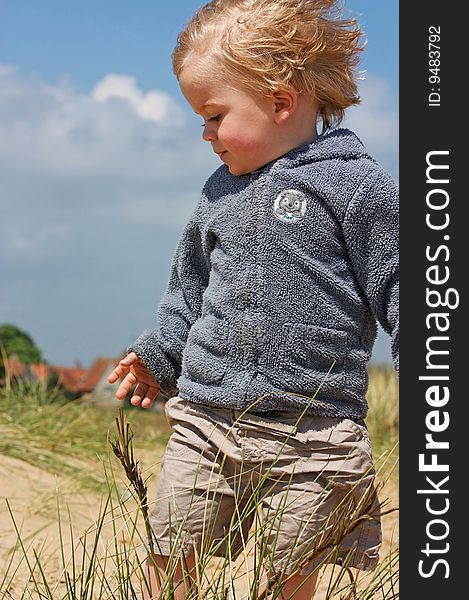 Close up of boy looking down in sand dunes. Close up of boy looking down in sand dunes