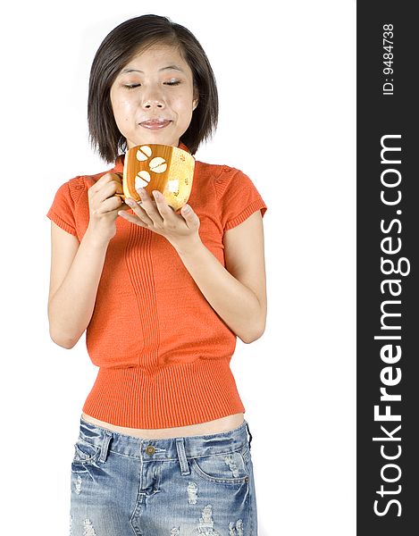 Charming Asian girl holding big mug with tea. Girl with kind face expression, wearing orange sweater. Charming Asian girl holding big mug with tea. Girl with kind face expression, wearing orange sweater.