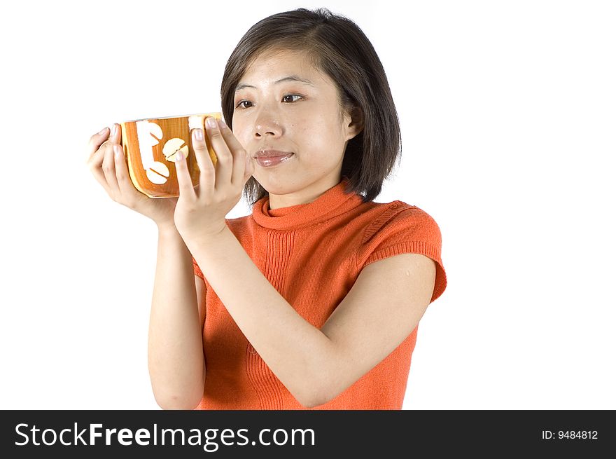 Charming Asian girl holding big mug with tea. Girl with kind face expression, wearing orange sweater. Charming Asian girl holding big mug with tea. Girl with kind face expression, wearing orange sweater.