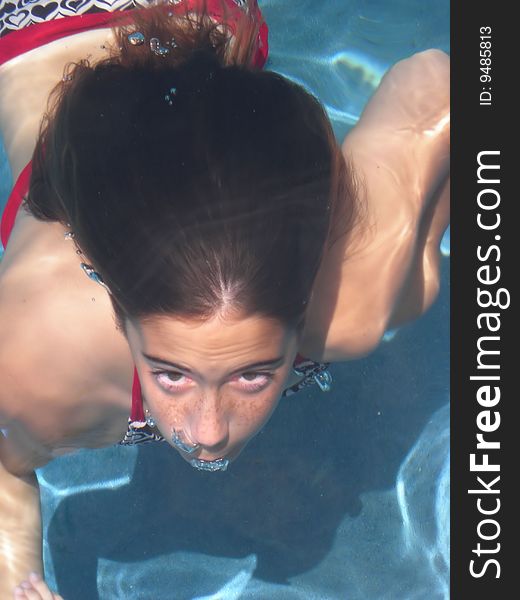 A young girl swimming underwater and blowing bubbles, ready to surface. A young girl swimming underwater and blowing bubbles, ready to surface.