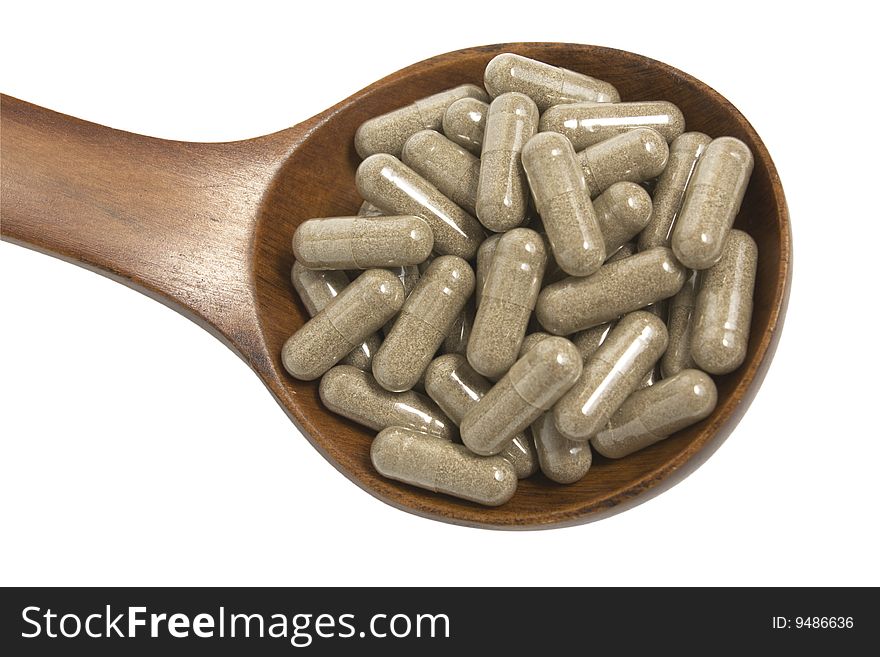 Pills in a wooden brown spoon on a white background it is isolated. Pills in a wooden brown spoon on a white background it is isolated