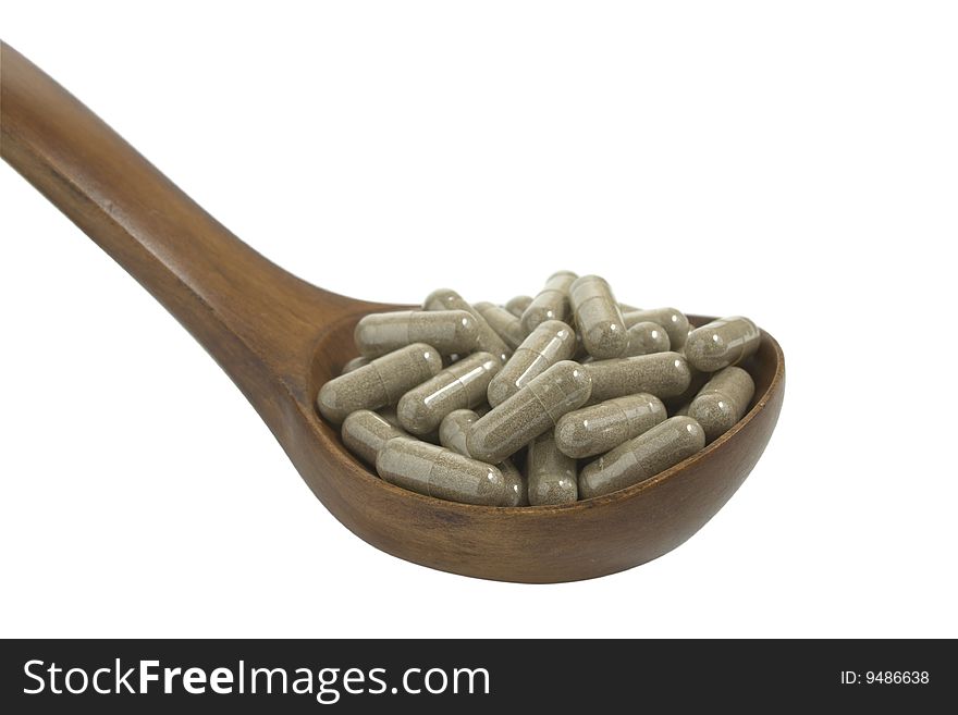Pills in a wooden brown spoon on a white background it is isolated. Pills in a wooden brown spoon on a white background it is isolated
