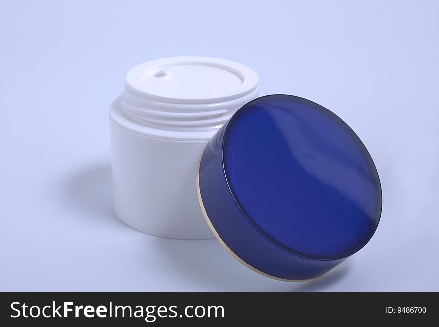 Tub with a face cream with a dark blue cover in blue light