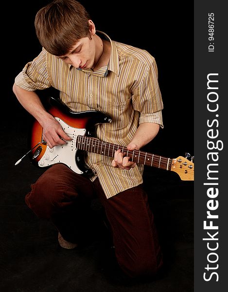 Young musician playing guitar isolated on black. Young musician playing guitar isolated on black.