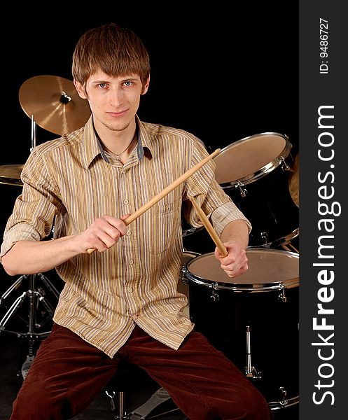 Young musician playing drums isolated on black. Young musician playing drums isolated on black.