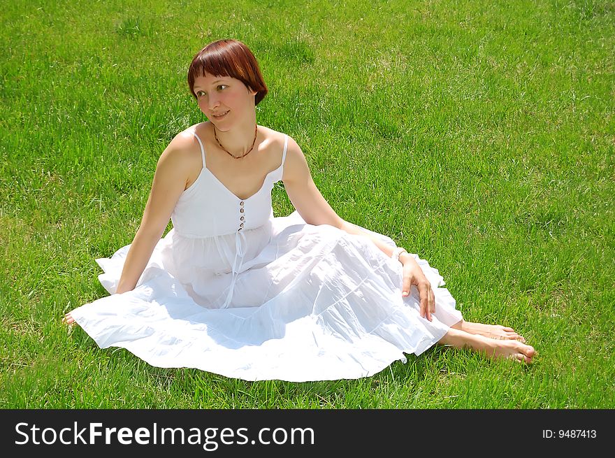 Beautiful young woman sitting on the grass. Beautiful young woman sitting on the grass.