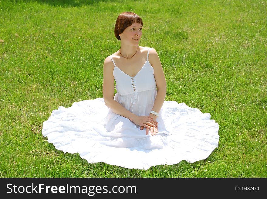 Beautiful young woman sitting on the grass. Beautiful young woman sitting on the grass.