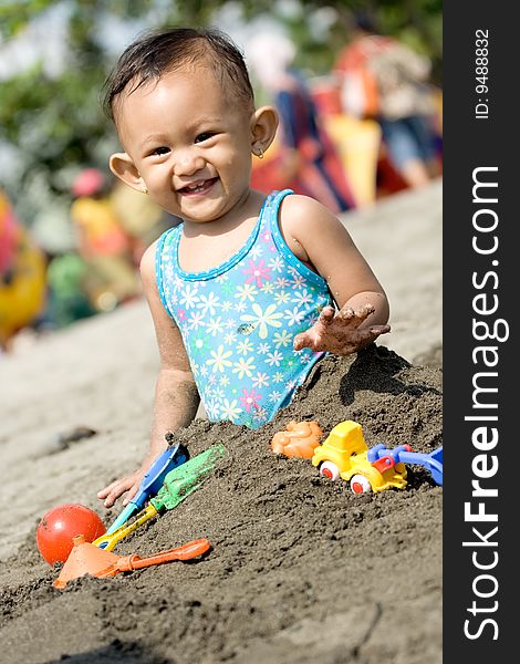 Cheerful asian baby girl enjoy playing with toys and sand on a hot sunny day at the beach. Cheerful asian baby girl enjoy playing with toys and sand on a hot sunny day at the beach