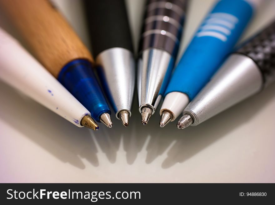 A row of ball point pens on white surface.