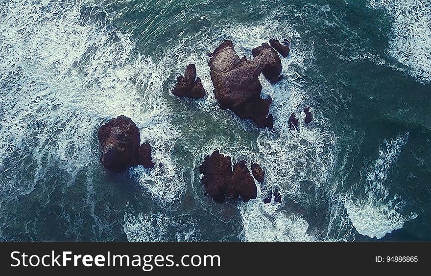 An aerial view of sea water splashing against rocks, California.