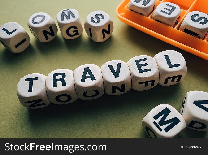 Upper case black letters on small white cubes with one complete meaningful word spelling "travel", green background.
