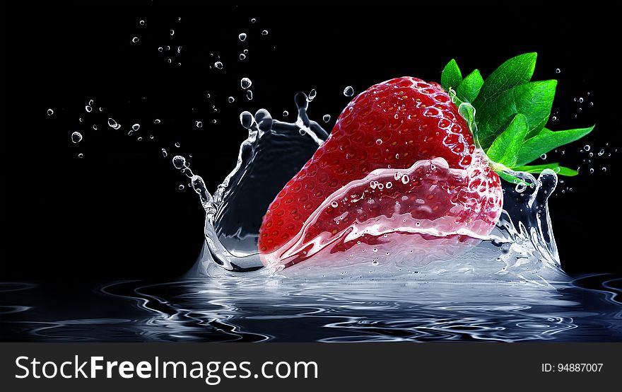 A close up of a strawberry splashing in water.