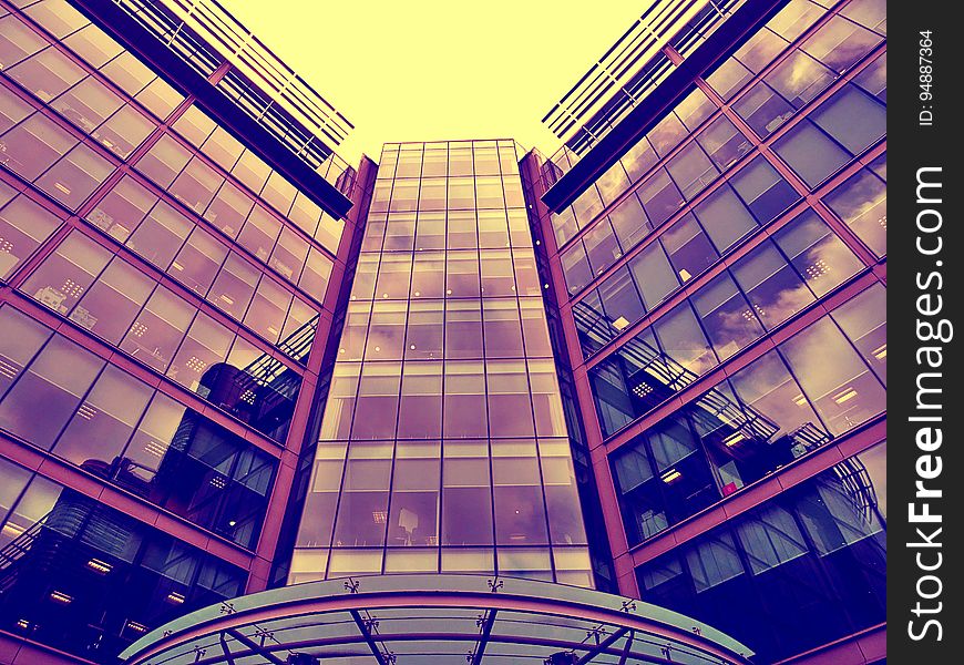 Modern downtown office building with city skyline reflecting in windows.