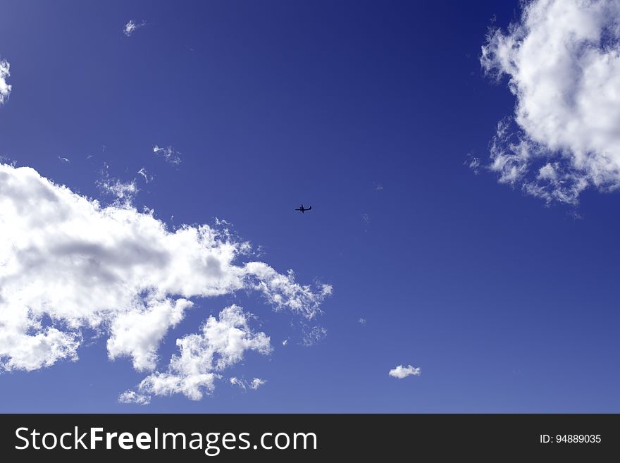 Airplane in the blue sky, between two clouds. Space for text. Airplane in the blue sky, between two clouds. Space for text.