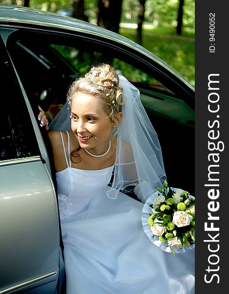 Young beautiful bride looking out of the car smiling