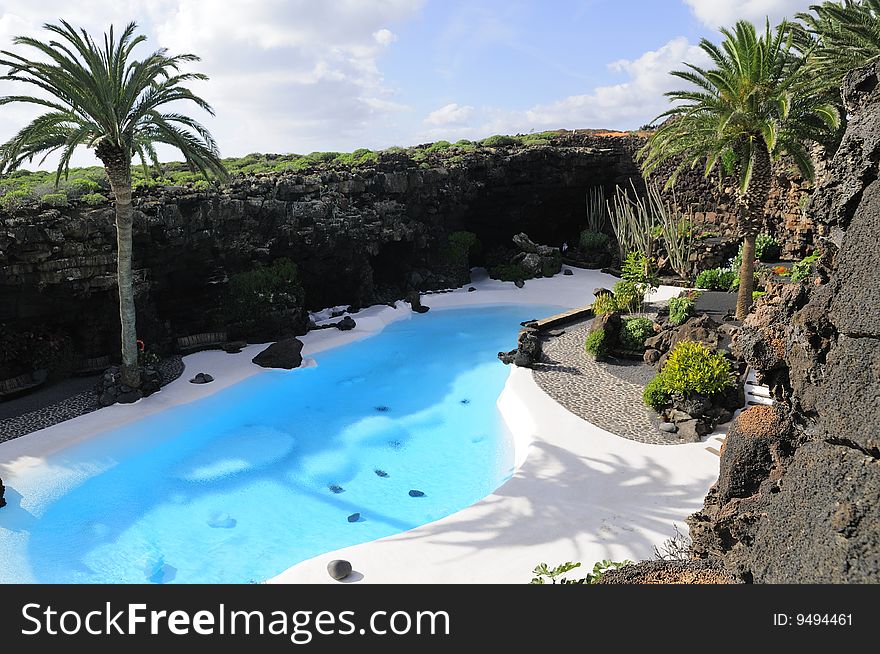 Swimming pool of blue water with palms and black rocks. Swimming pool of blue water with palms and black rocks