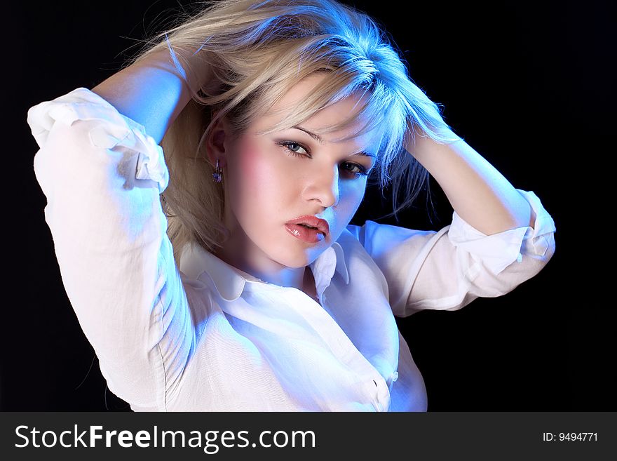 Young blondie girl under blue light against black background