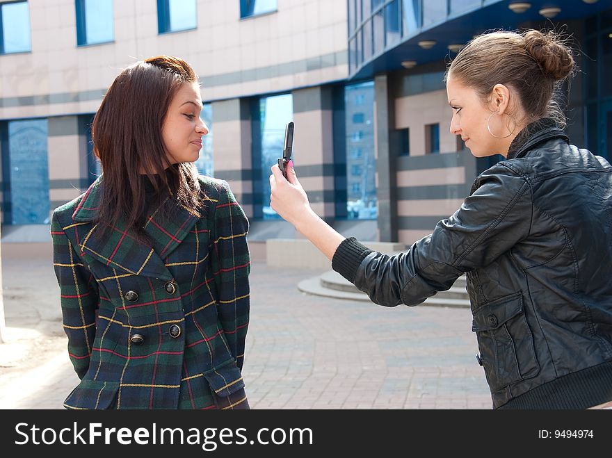 Two Girls Take Pictures On A Street