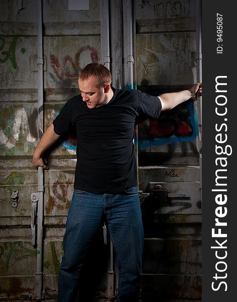 Powerful man expression portrait in a dark near container with graffiti