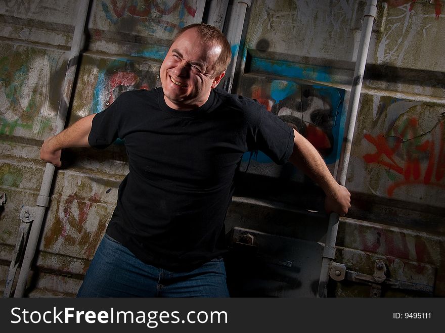 Powerful man expression portrait in a dark near container with graffiti