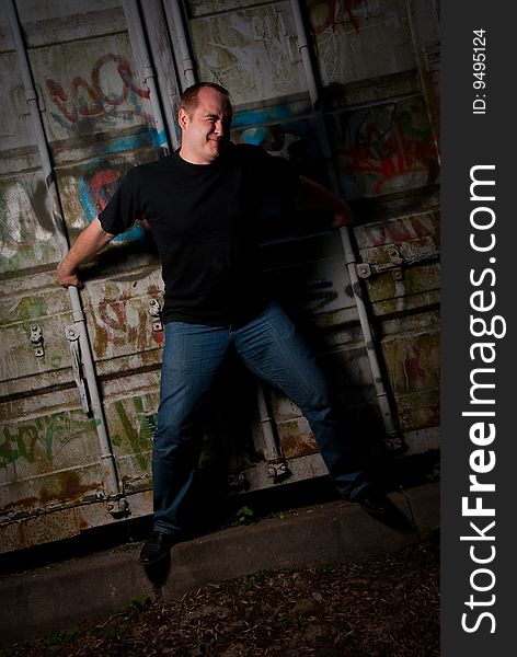 Powerful man expression portrait in a dark near container with graffiti