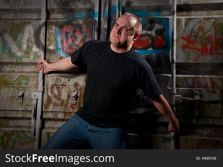 Powerful man expression portrait in a dark near container with graffiti