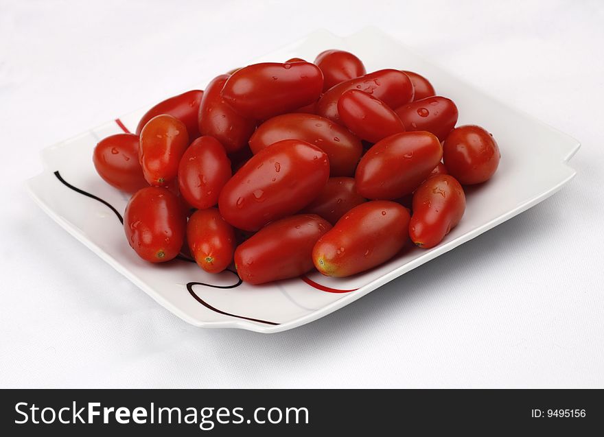 Tomatoes cherry on a white plate and on a white cloth