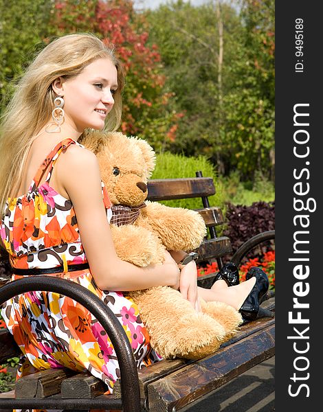 Attractive blond caucasian woman with teddy bear in summer park. Attractive blond caucasian woman with teddy bear in summer park