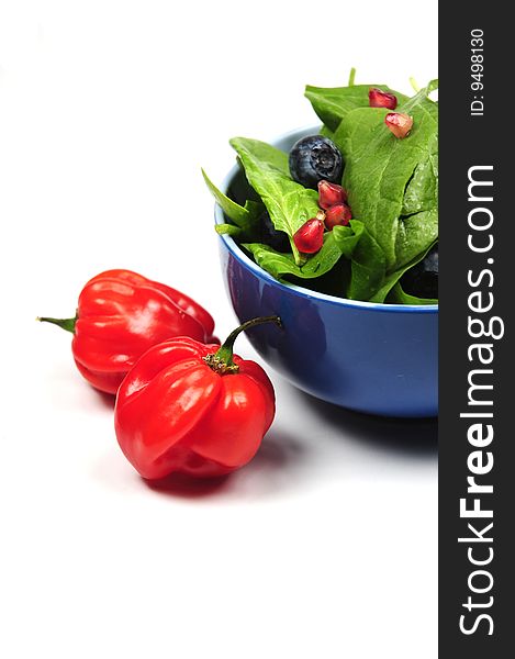 Two ripe and red peppers next to a bowl of fresh salad. Two ripe and red peppers next to a bowl of fresh salad.