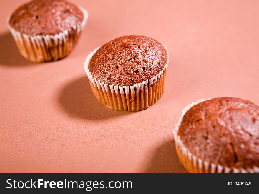 Three chocolate muffins on brown background