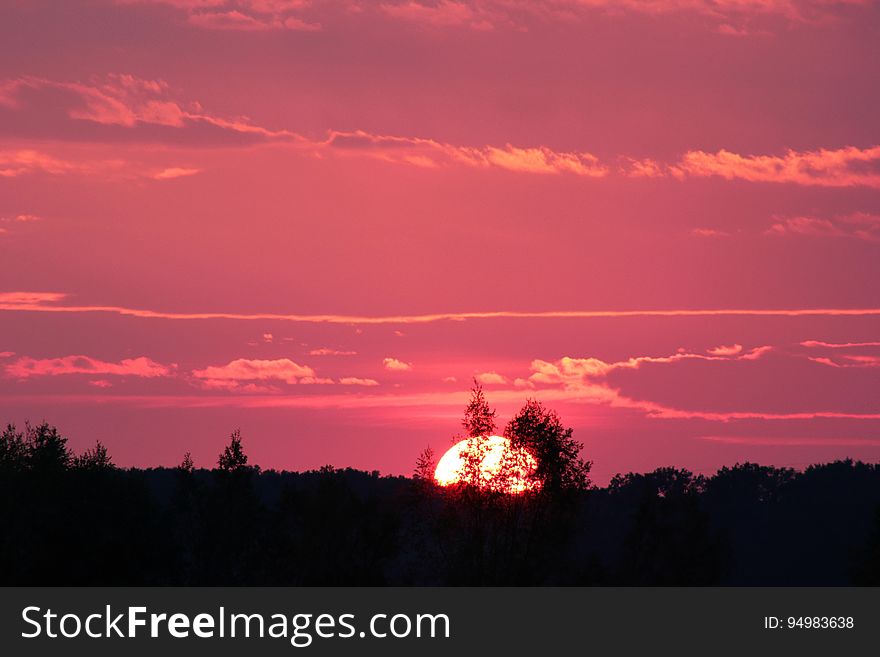 Silhouette of trees in landscape against red sunset in skies. Silhouette of trees in landscape against red sunset in skies.