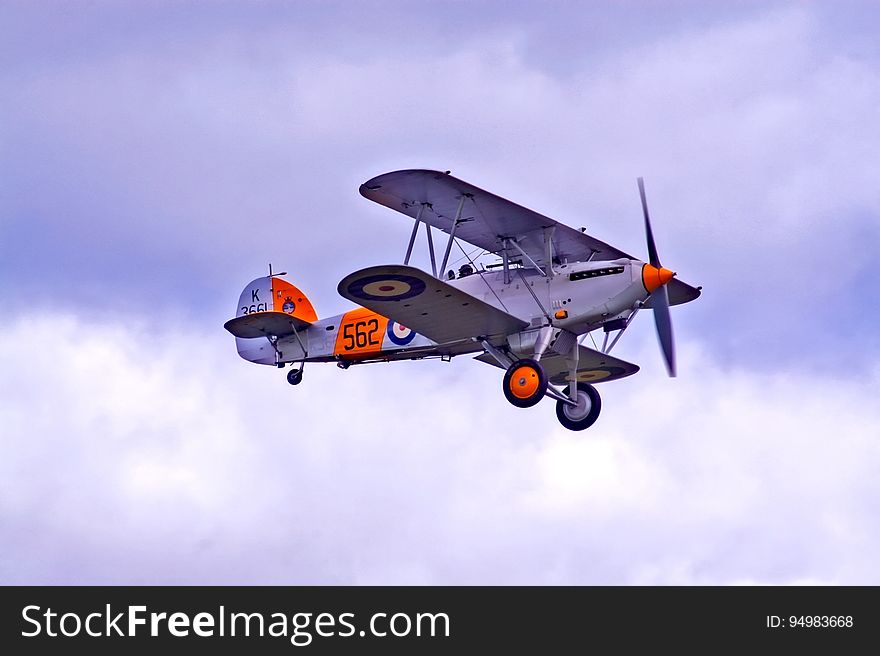 Vintage military prop plane in skies against clouds.