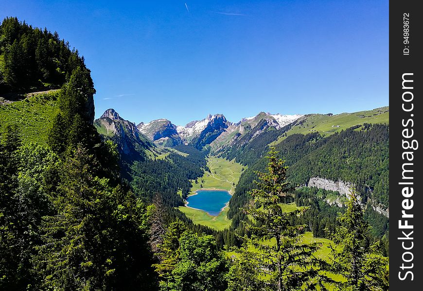 Lake surrounded by forest in alpine valley on sunny day with blue skies. Lake surrounded by forest in alpine valley on sunny day with blue skies.
