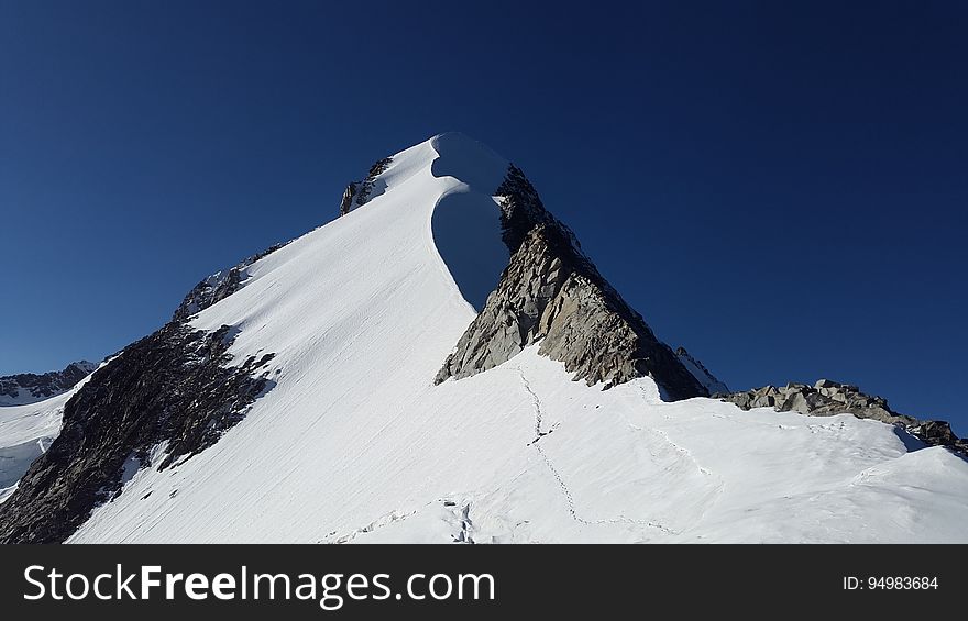 A snow-covered mountain peak and blue sky. A snow-covered mountain peak and blue sky.