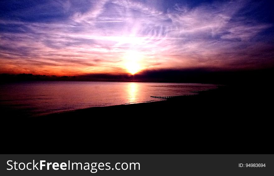 Sunset through clouds over beach. Sunset through clouds over beach.