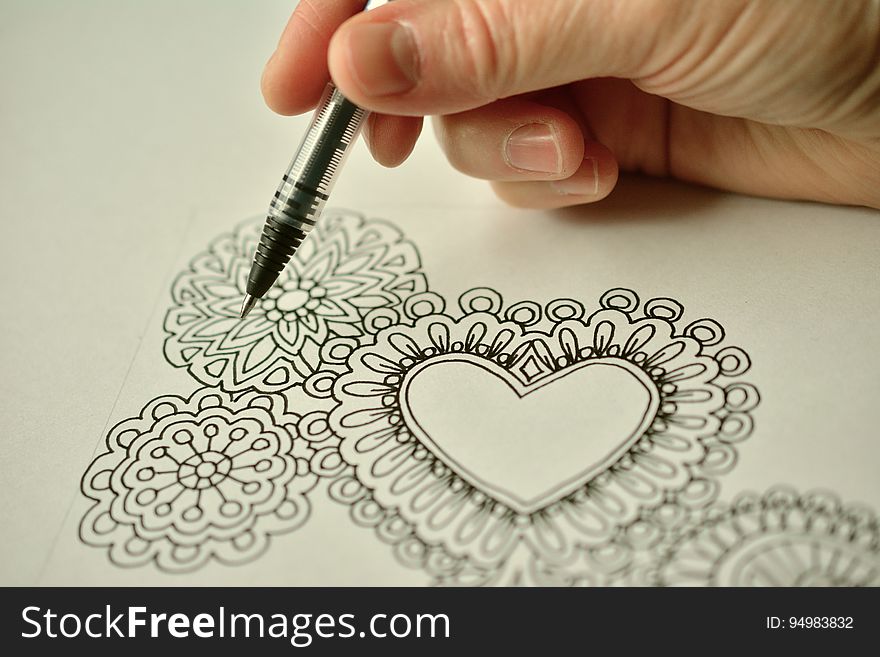 A person doing a line art drawing with heart and flower shapes. A person doing a line art drawing with heart and flower shapes.
