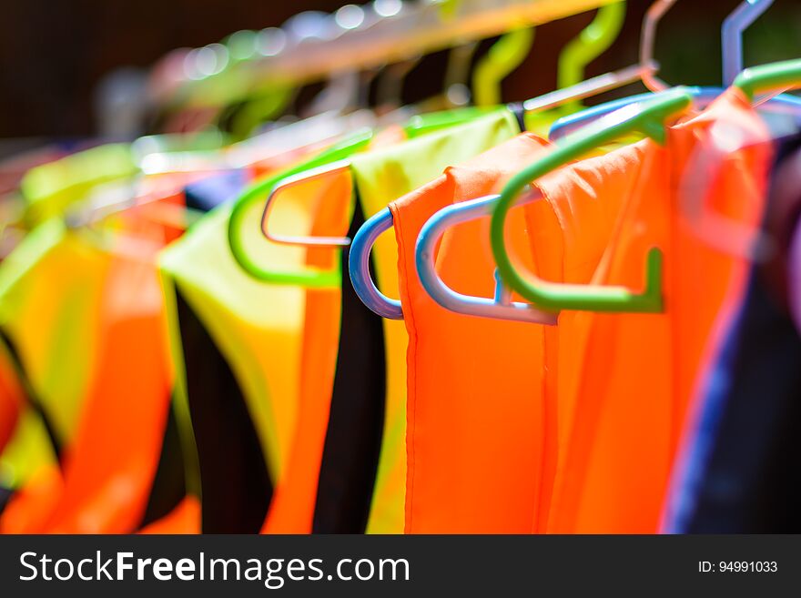 Colorful Life Jackets Hanging On A Bar.