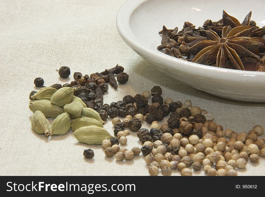 Close up shot of various spices including star anise, cardamon, coriander, black pepper and cloves some in a bowl. Close up shot of various spices including star anise, cardamon, coriander, black pepper and cloves some in a bowl