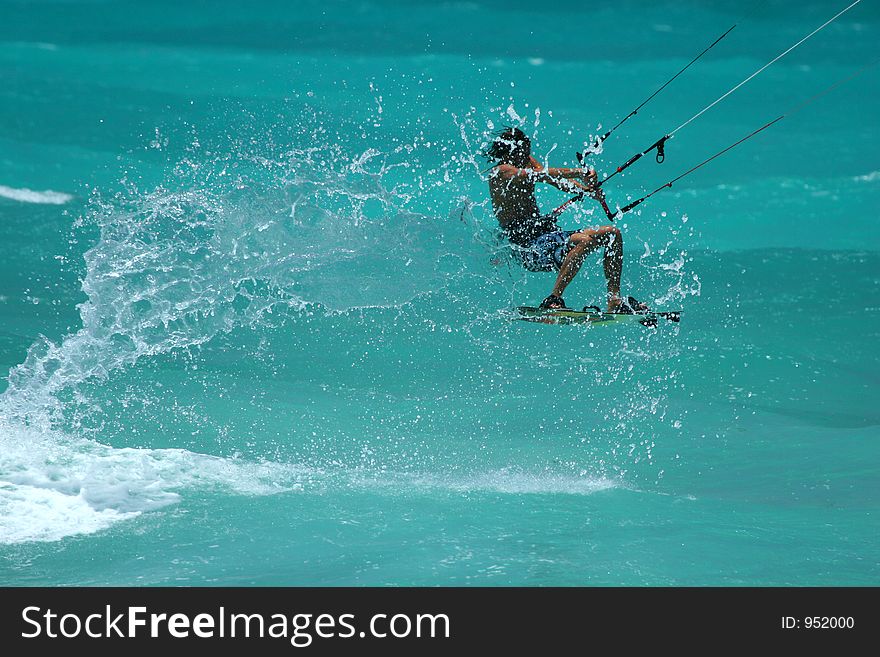 Kite surfer jumps, throwing up lots of spray. Kite surfer jumps, throwing up lots of spray.