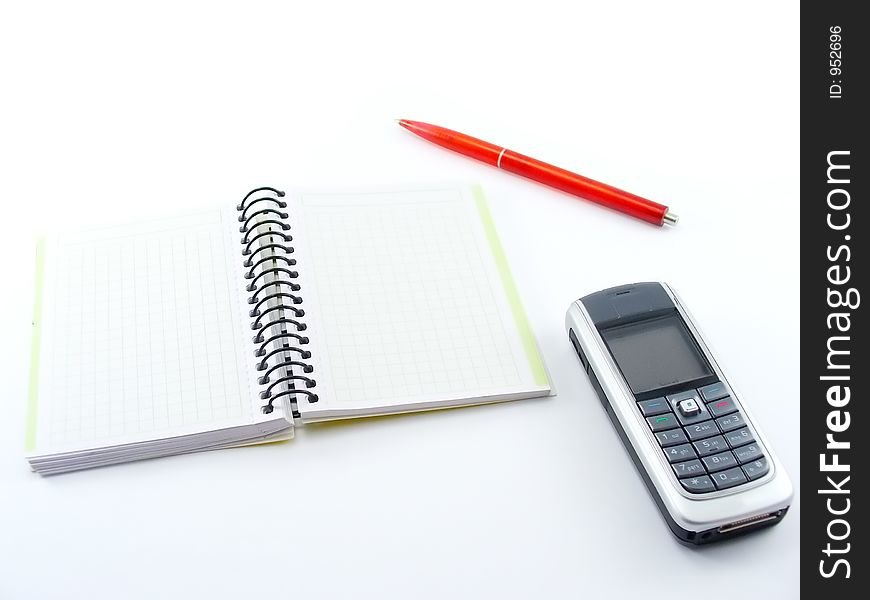 Notebook with cell phone and red pen on white table