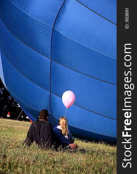 Colorful Hot Air Balloon on Ground with Father and Daughter sitting and Watching