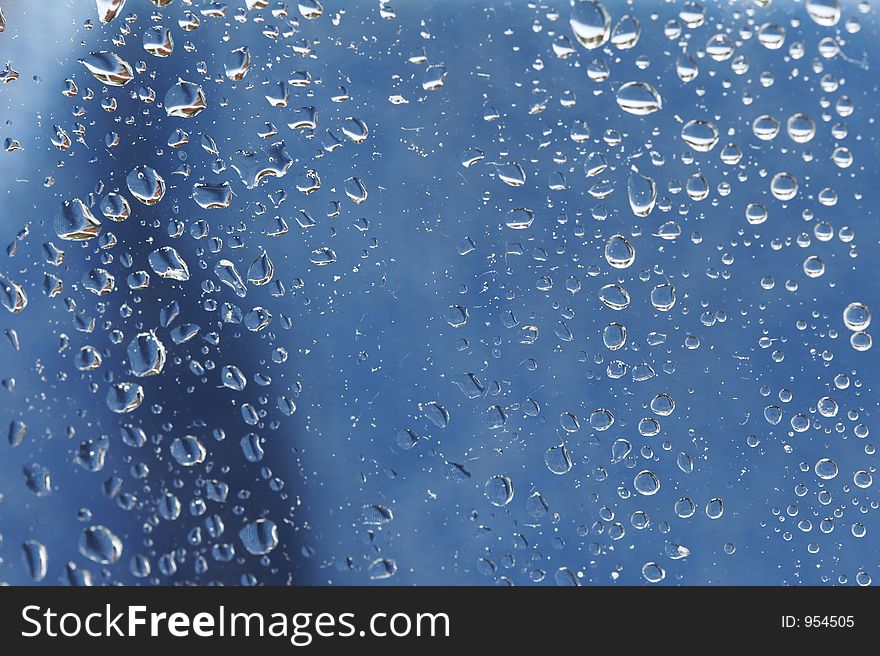 Raindrops at a window - blue background. Raindrops at a window - blue background