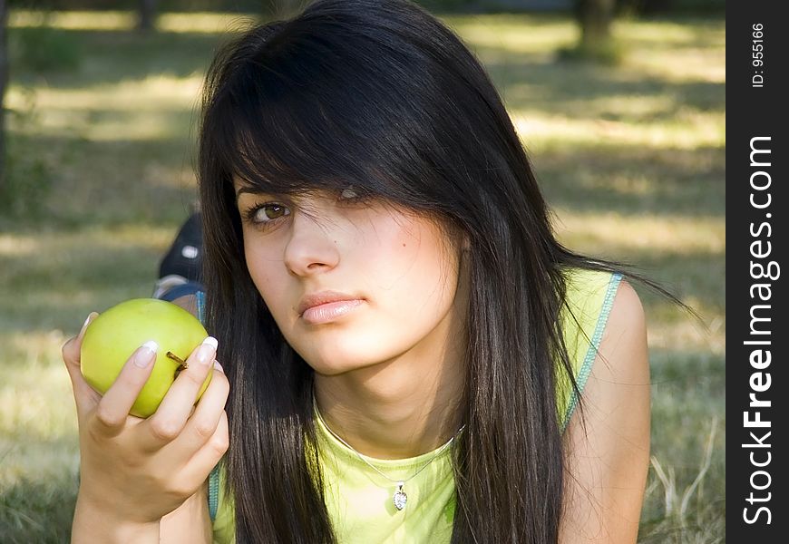 Beautiful girl lying on grass and holding green apple in hand. Beautiful girl lying on grass and holding green apple in hand