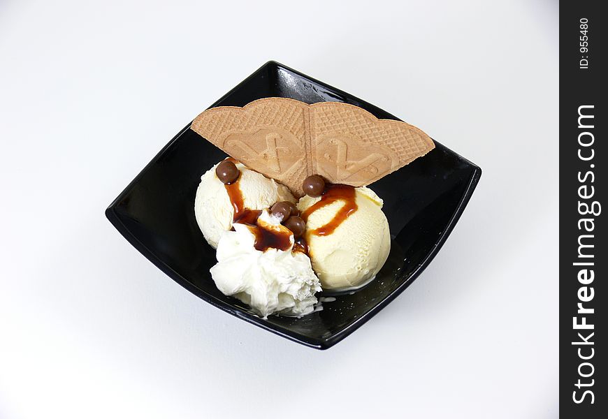 A vanilla icecream dessert with chocolate syrup and a wafer