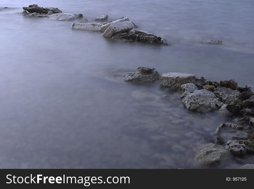 Long exposure image of a rocky coast, which gives the water a mystic effect.