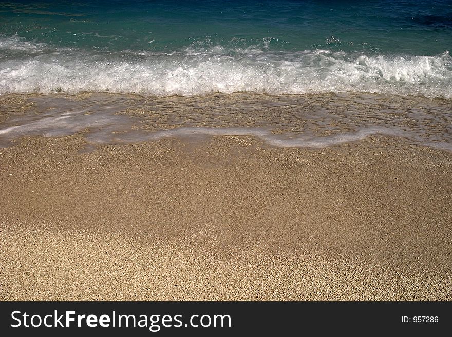 White waves from the blue ocean arriving at a tropical beach.