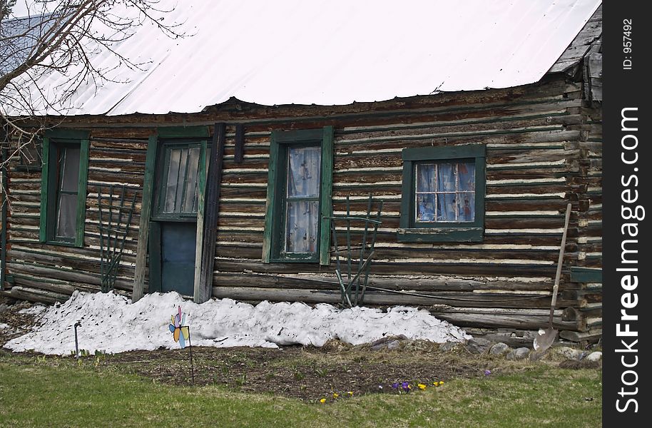 This image of the old house with the sagging roof, shovel, snow, and flowers was taken in western MT. This image of the old house with the sagging roof, shovel, snow, and flowers was taken in western MT.